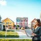 A modern suburban neighborhood showcasing a diverse range of eligible properties for FHA loans, including a charming single-family home with a well-maintained lawn, a small apartment building, and a cozy townhouse. In the foreground, a professional couple in modest business attire reviews property requirements on a clipboard. The middle ground features the homes in vibrant colors with visible "For Sale" signs. The background shows a clear blue sky and a few fluffy clouds, creating a welcoming atmosphere. Soft, bright lighting enhances the scene, suggesting a sunny afternoon. The angle is slightly elevated, capturing the essence of community living and the concept of property eligibility, perfectly aligning with FHA requirements. - how to get a usda loan