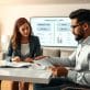 A visually engaging scene illustrating the concept of a home equity loan. In the foreground, a diverse group of two professionals, a woman and a man, are seated at a sleek modern desk, both dressed in smart business attire, examining financial documents that reflect loan options. In the middle layer, a large computer screen displays a clear infographic comparing a home equity loan and a HELOC, with graphs and numbers. In the background, a cozy, well-furnished living room with a contemporary aesthetic, featuring a bookshelf and potted plants. The lighting is warm and inviting, creating a productive atmosphere. The angle captures the professionals’ expressions of focus and determination, accentuating the serious yet approachable nature of financial planning. - is fha loan better than conventional